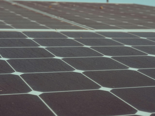 Green sustainable home with solar panels and electric vehicle representing eco-friendly living